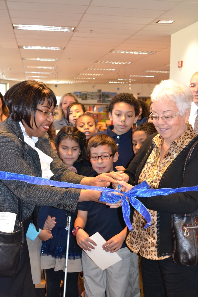 Mrs. Candy Carson and Dorris Lumsden cut the ribbon on the new Ben Carson Reading Room while Maxwell students gather in anticipation.